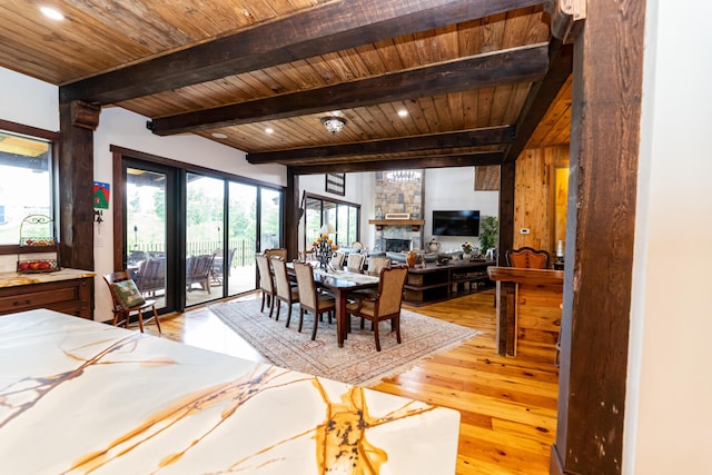 dining space with beam ceiling, wood ceiling, a fireplace, and light hardwood / wood-style flooring