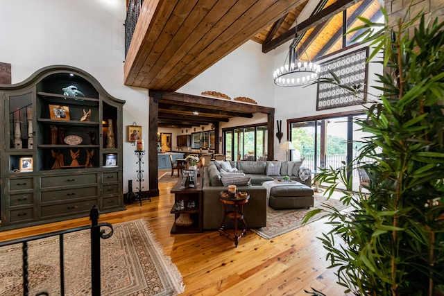 living room with wood ceiling, light hardwood / wood-style flooring, high vaulted ceiling, an inviting chandelier, and beamed ceiling