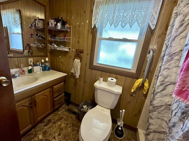 bathroom with vanity, toilet, and wooden walls