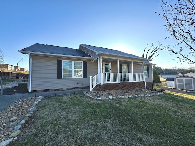 single story home with fence, a porch, a front yard, an outdoor structure, and a storage unit