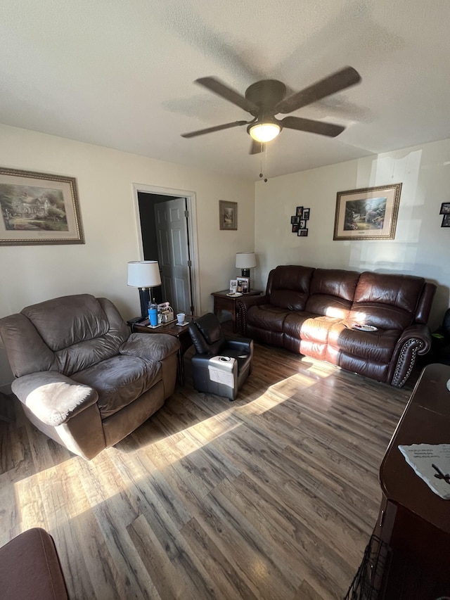 living room with a textured ceiling, dark hardwood / wood-style flooring, and ceiling fan