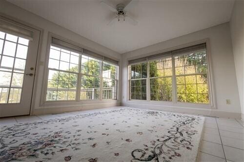 unfurnished sunroom featuring plenty of natural light, ceiling fan, and french doors