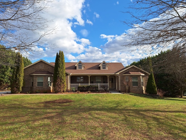 view of front of property with a porch, a front yard, and brick siding