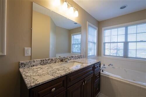 bathroom featuring vanity and tiled tub