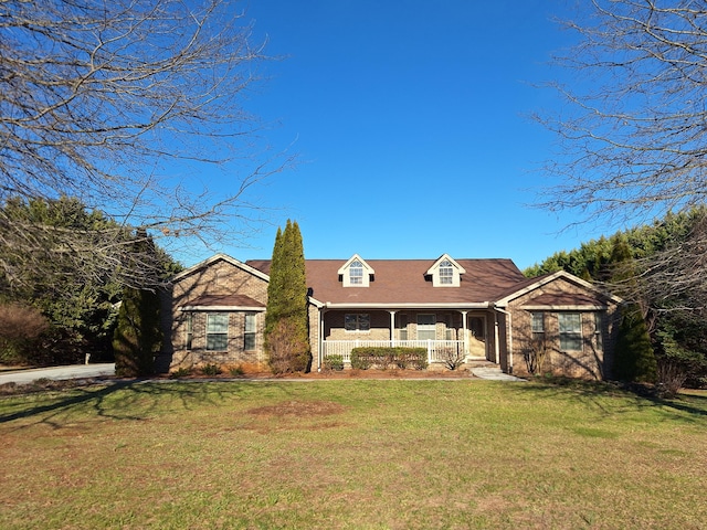 cape cod home featuring brick siding, a porch, and a front yard