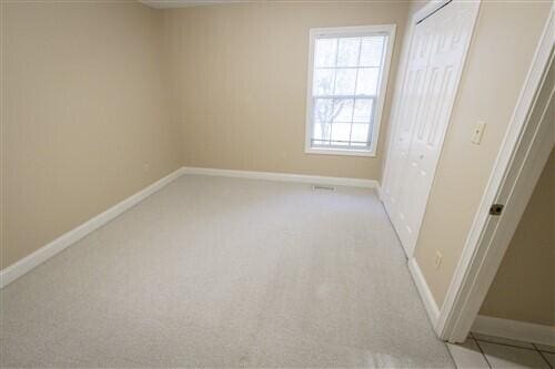 unfurnished bedroom featuring a closet and light colored carpet