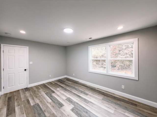 spare room featuring baseboards, visible vents, wood finished floors, and recessed lighting