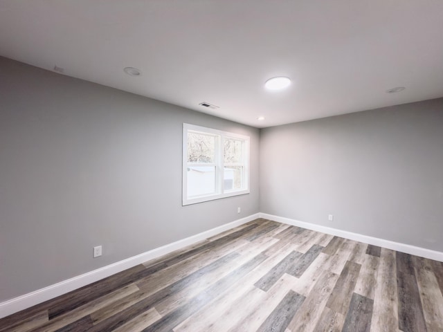 empty room with visible vents, baseboards, and wood finished floors