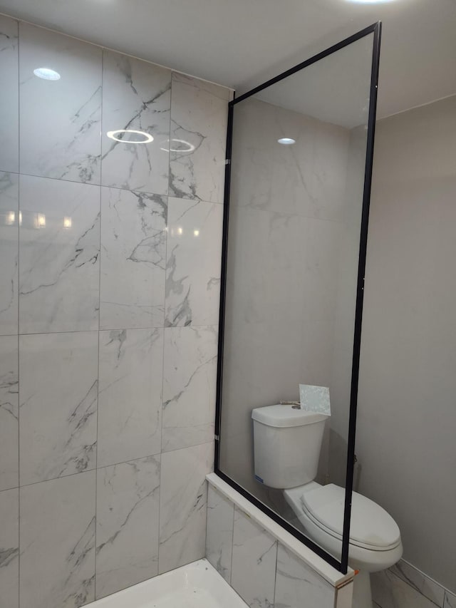 bathroom with toilet, marble finish floor, and a shower