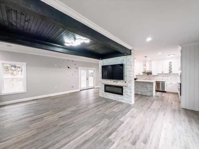 unfurnished living room with beam ceiling, french doors, a fireplace, light wood-style floors, and baseboards