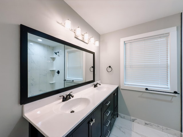 full bath with double vanity, marble finish floor, baseboards, and a sink