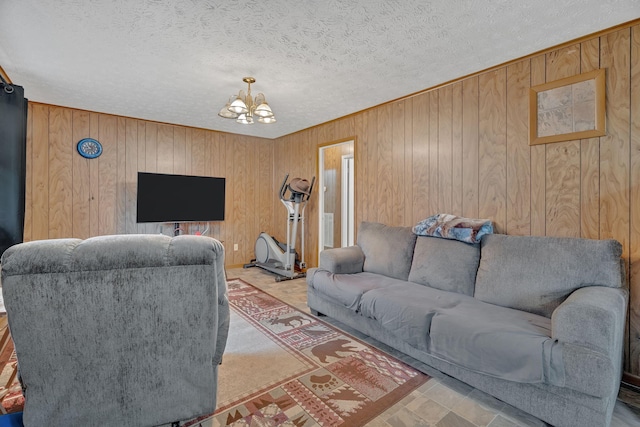 living room featuring a notable chandelier, wood walls, and a textured ceiling