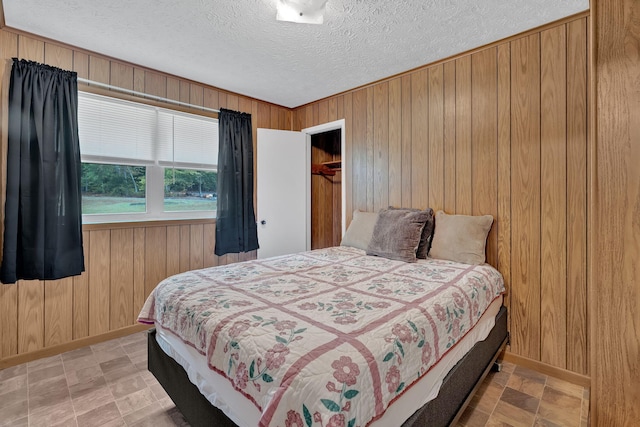 bedroom with wood walls, a textured ceiling, and a closet