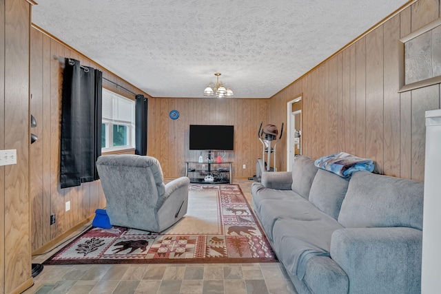 living room with a textured ceiling, a notable chandelier, and wood walls