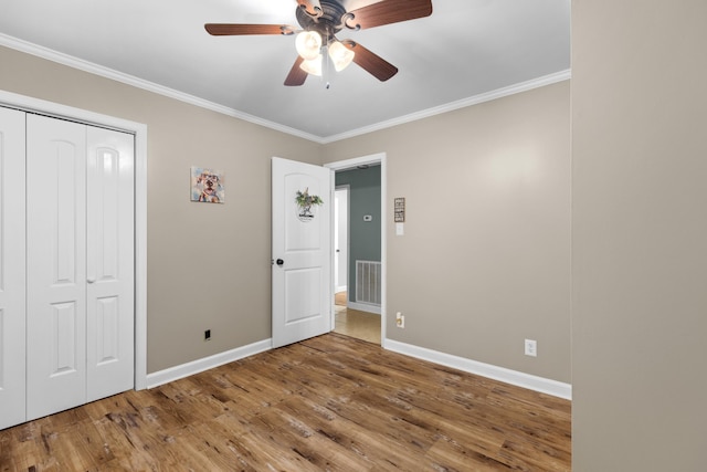 unfurnished bedroom with hardwood / wood-style floors, ceiling fan, crown molding, and a closet