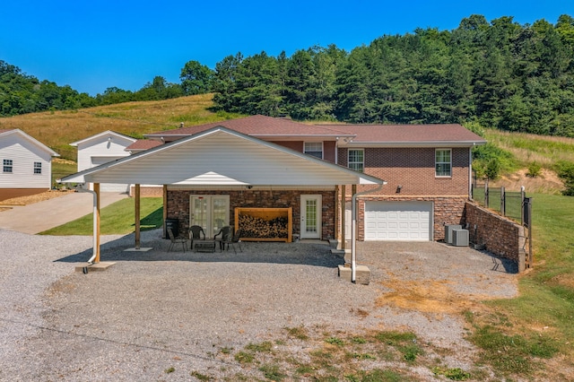 view of front of property featuring a front yard, central AC, and a garage