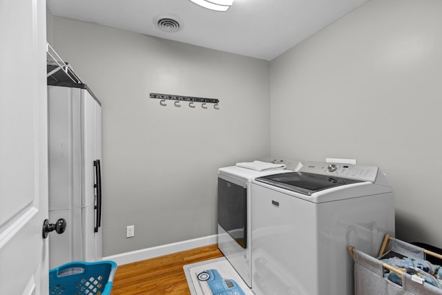 laundry area featuring separate washer and dryer and light hardwood / wood-style floors