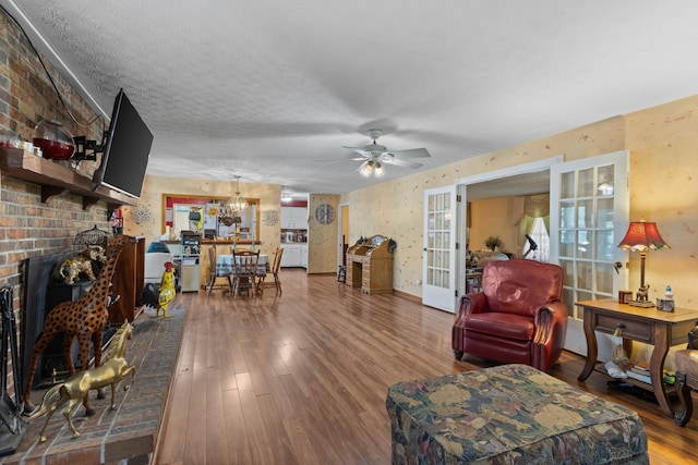 living room featuring hardwood / wood-style floors, ceiling fan with notable chandelier, and a textured ceiling