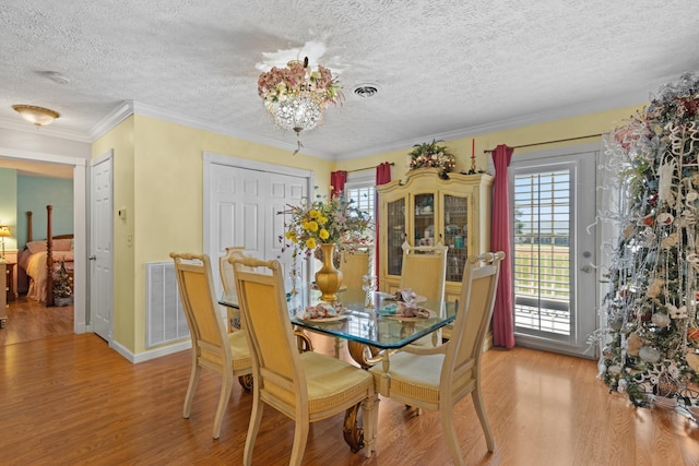 dining room with crown molding, a chandelier, a textured ceiling, and light hardwood / wood-style floors