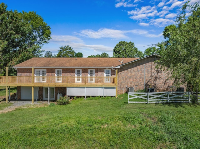 rear view of property featuring a lawn, central AC unit, a garage, and a deck