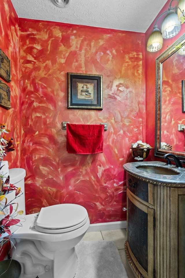 bathroom with tile patterned floors, vanity, a textured ceiling, and toilet