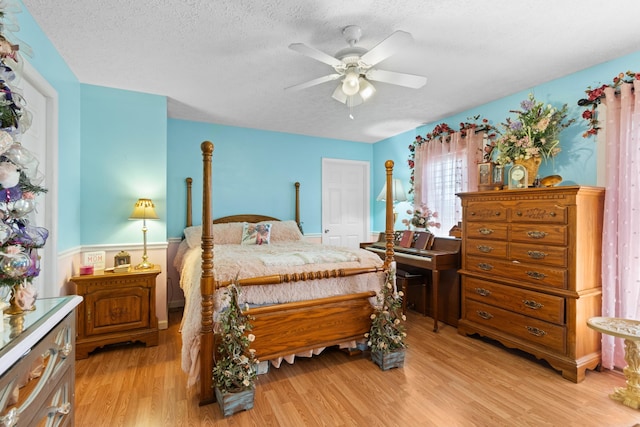 bedroom featuring ceiling fan, light wood-type flooring, and a textured ceiling