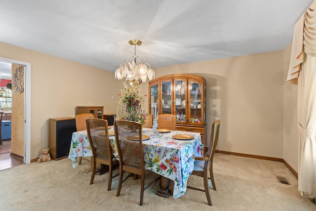 dining area featuring a notable chandelier and light carpet