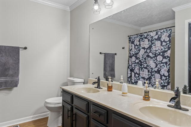 bathroom with double vanity, ornamental molding, a sink, and toilet