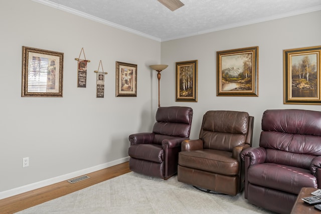 cinema room with visible vents, baseboards, light wood-style flooring, ornamental molding, and a textured ceiling