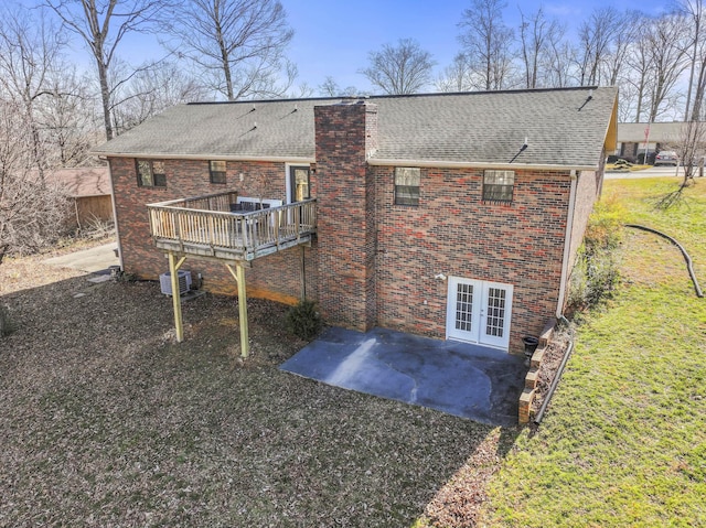 rear view of property with french doors, brick siding, a chimney, central AC unit, and a deck