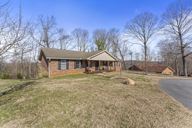 view of front of house with covered porch, brick siding, a front lawn, and a shingled roof