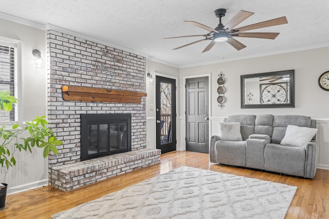 living area with a textured ceiling, ornamental molding, a fireplace, and hardwood / wood-style flooring