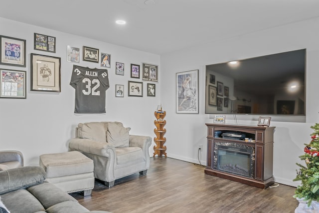 living room featuring recessed lighting, baseboards, wood finished floors, and a glass covered fireplace