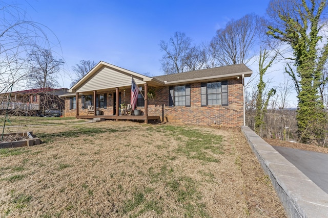 ranch-style house featuring roof with shingles, brick siding, a porch, and a front yard