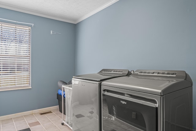 clothes washing area with a textured ceiling, laundry area, baseboards, ornamental molding, and washing machine and clothes dryer