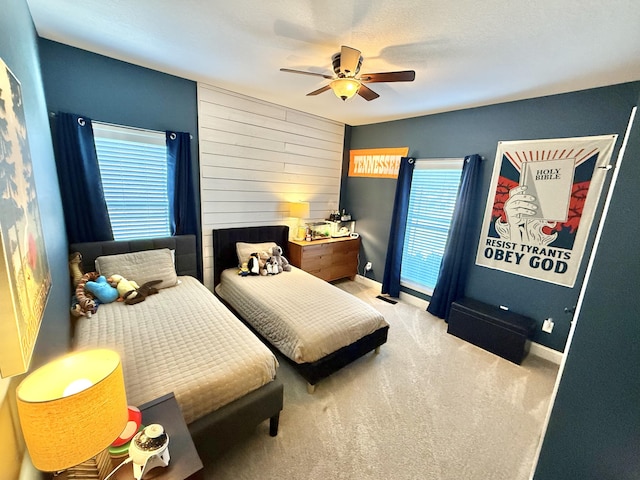 bedroom with baseboards, wooden walls, ceiling fan, and carpet