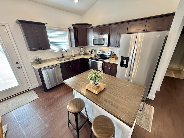 kitchen featuring stainless steel appliances, decorative backsplash, a sink, and dark brown cabinetry