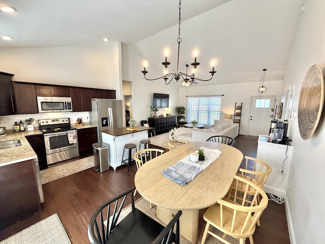 dining space featuring recessed lighting, a notable chandelier, high vaulted ceiling, and dark wood finished floors
