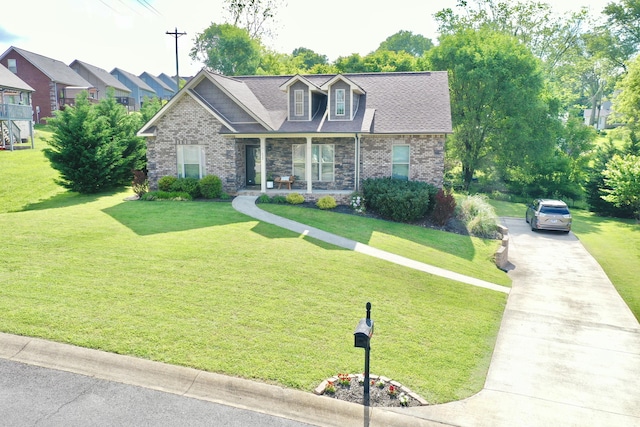 view of front of home with covered porch, concrete driveway, a front yard, and stone siding