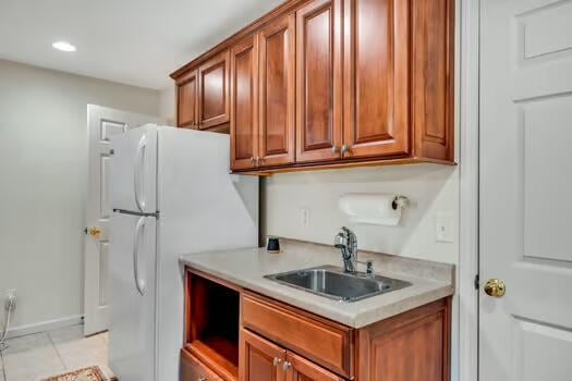 784 Constitution Dr, Jefferson City, TN 37760 - kitchen with light tile patterned floors, light countertops, brown cabinetry, freestanding refrigerator, and a sink