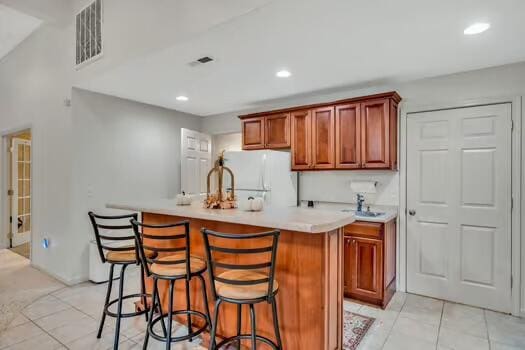 784 Constitution Dr, Jefferson City, TN 37760 - kitchen featuring light tile patterned floors, visible vents, freestanding refrigerator, light countertops, and a kitchen bar