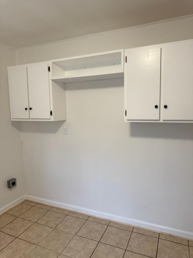 laundry room with cabinet space, light tile patterned floors, baseboards, and electric dryer hookup