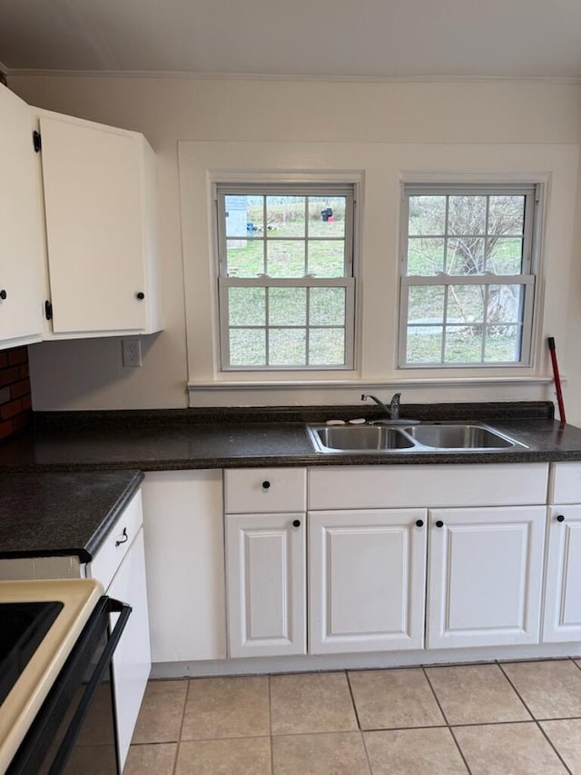 kitchen featuring light tile patterned floors, dark countertops, a sink, and white cabinets