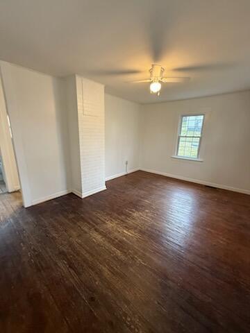 empty room with dark wood-style floors, baseboards, and a ceiling fan