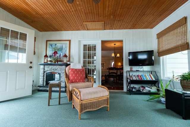 sitting room with wood ceiling, a fireplace, a chandelier, and carpet flooring