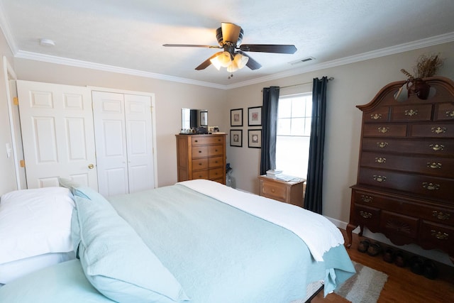 bedroom with dark hardwood / wood-style flooring, ornamental molding, ceiling fan, and a closet