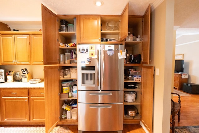 kitchen with stainless steel fridge, crown molding, and light hardwood / wood-style floors