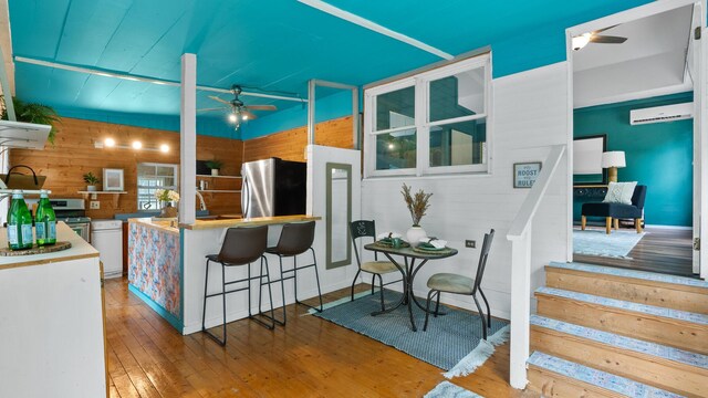 261 Buzzard Roost Rd, Bulls Gap, TN 37711 - kitchen with ceiling fan, wooden walls, stainless steel appliances, a wall mounted AC, and hardwood / wood-style flooring