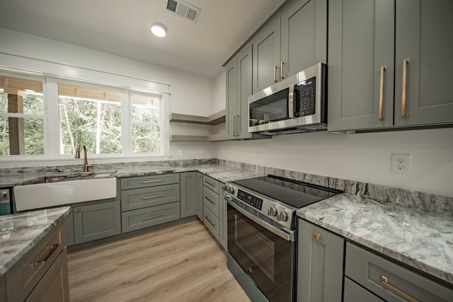 1056 Old Newport Hwy, Dandridge, TN 37725 - kitchen with appliances with stainless steel finishes, gray cabinetry, light stone countertops, and light wood finished floors