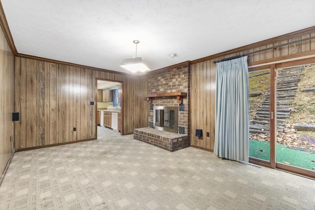 unfurnished living room featuring wooden walls, light colored carpet, a brick fireplace, and crown molding